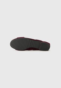 Scarpa in suede bordeaux con suola in gomma, caratterizzata da un motivo rigato per una migliore aderenza. Il design presenta un profilo basso con una finitura liscia.
