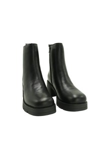 Un par de botas de cuero negras hasta el tobillo con tacones gruesos y cremalleras laterales sobre fondo blanco.