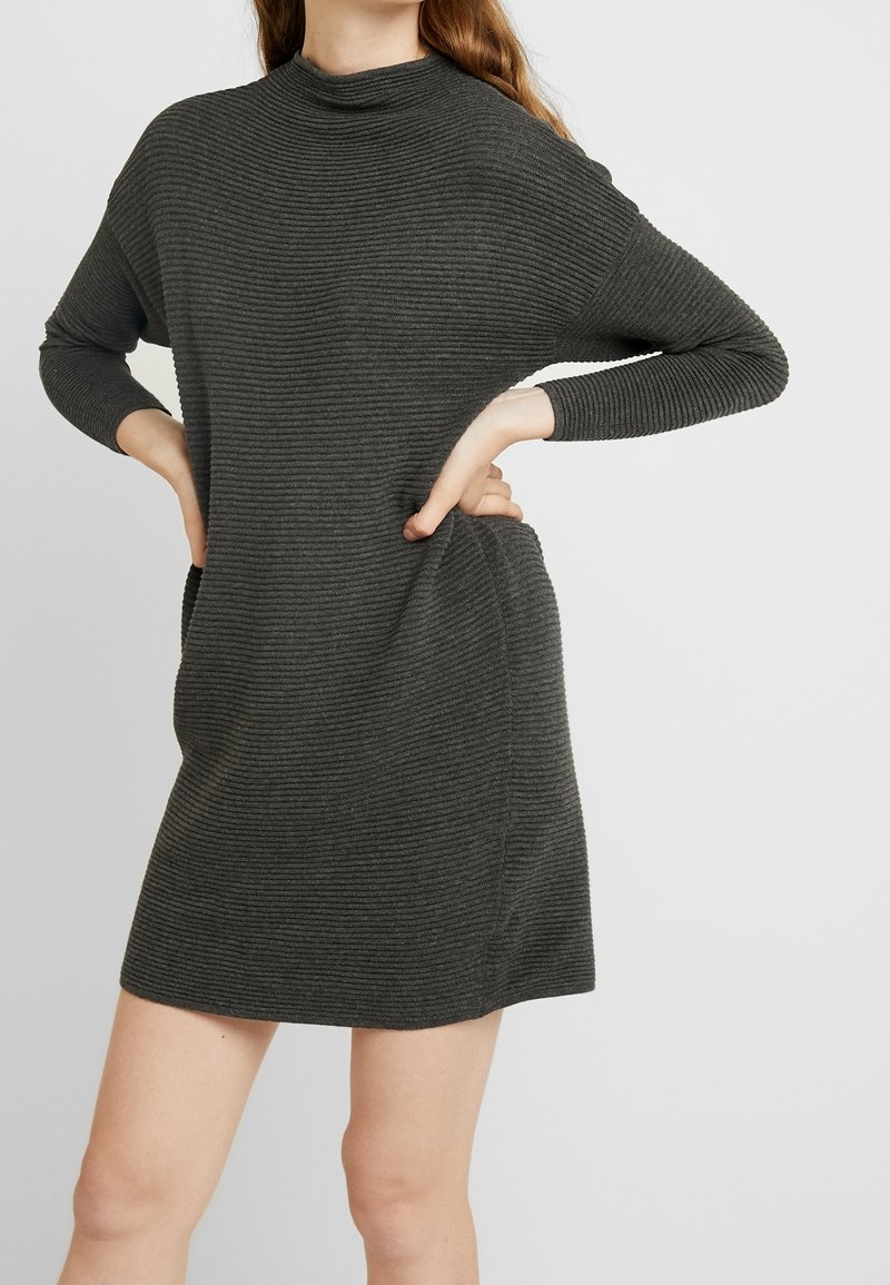 Robe côtelée gris foncé en maille, à col montant et manches longues, avec poches latérales et une silhouette décontractée légèrement évasée.