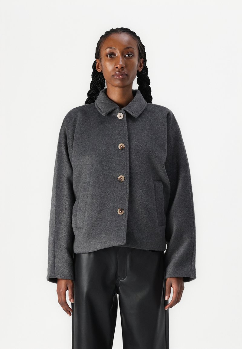 Veste en mélange de laine grise avec un col, cinq boutons en bois et poches sur les côtés. Présente une coupe décontractée et des manches longues.