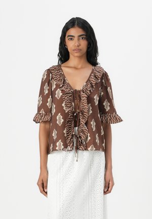 Brown patterned blouse with ruffled sleeves, a deep V-neck, and tie closure at the front. Features leaf motifs in cream against a textured background.