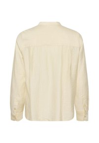 Chemise texturée écrue à manches longues avec poignets boutonnés, vue de dos sur un fond uni.
