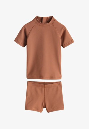 Set rash guard in colore ruggine, composto da una maglia a maniche corte con collo alto e pantaloncini abbinati, entrambi realizzati in tessuto testurizzato.