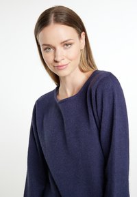 Marineblauer Strickpullover mit weitem, rundem Ausschnitt und fallenden Schultern. Weiche Textur mit lässiger Passform, die ein schlichtes, klassisches Design zur Schau stellt.