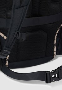 Zaino nero con tessuto a rete, spallacci imbottiti e fibbia regolabile. Presenta un dettaglio a motivo beige e nero.