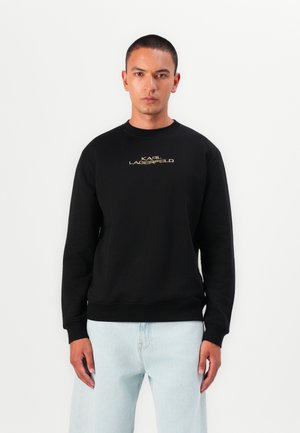 Sweatshirt noir en mélange de coton, avec un col rond et des poignets côtelés. Texte doré "KARL LAGERFELD" centré sur la poitrine.