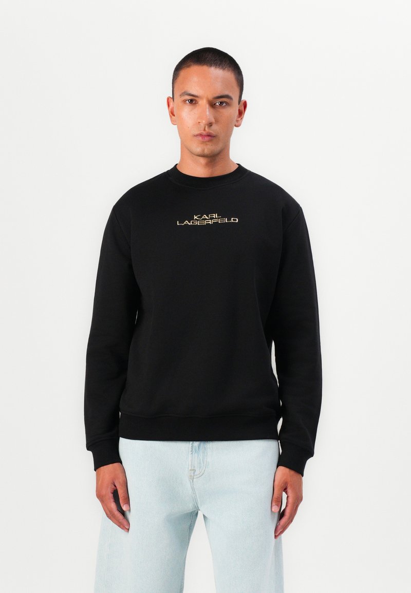 Sweatshirt preto feito de mistura de algodão, com gola redonda e punhos canelados. Texto dourado "KARL LAGERFELD" centrado no peito.