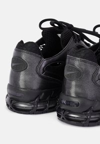 Para czarnych sportowych sneakersów z widocznymi podeszwami z poduszką powietrzną i siateczkową tkaniną przy sznurowadłach, widziana od tyłu.