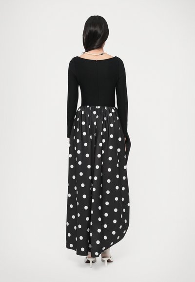 Pikk kleit, millel on vormitud must top ja voolav must seelik, millel on suured valged täpid, tagaküljel lukk ja pikad varrukad.