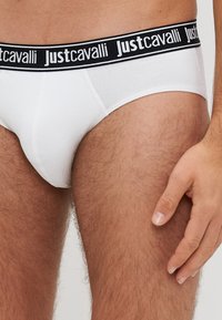 Chiloți albi din bumbac, cu o brățară elastică neagră, având logo-ul "Justcavalli". Textură netedă, design adaptat pe corp și formă jos.