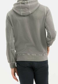 Gray hooded sweatshirt with a soft, textured fabric. Features a drawstring hood, ribbed cuffs, and seams along the sides. Simple design.