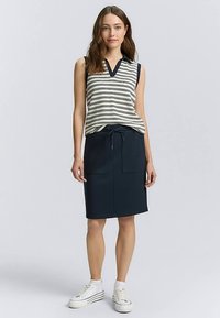 Striped sleeveless top in cream and navy with V-neck, paired with a navy drawstring skirt featuring two front pockets and a fitted shape.