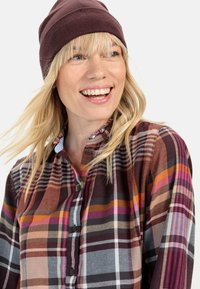 Rutet skjorte med rige farver som lilla, orange og grå, med en knaplukning og flæsekrave. Sæt sammen med en mørkebrun beanie.