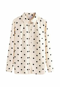 Chemise à manches longues en tissu crème avec des pois noirs, fermeture à boutons sur le devant et col classique. Dispose de deux poches à l'avant.
