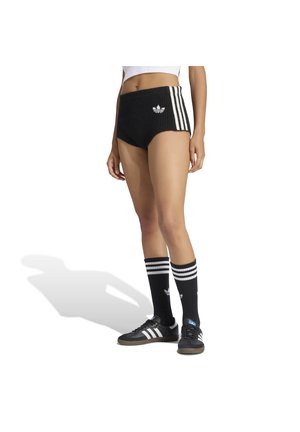 Personne portant un short côtelé noir avec des rayures blanches, des chaussettes noires hautes avec des rayures blanches, et des baskets noires avec des rayures blanches.