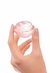 Masque pour les lèvres au collagène PDRN Abib dans un pot rond et transparent tenu par une main, présentant une texture gélatineuse rose avec des bulles visibles à la surface.