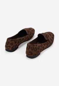 Chaussures à enfiler en imprimé léopard marron avec une texture douce semblable à du daim et une semelle en caoutchouc noir basse. Bout arrondi avec un détail de sangle subtil.