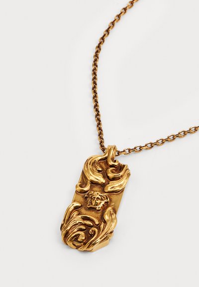 Collana con pendente in tono oro, caratterizzata da un design testurizzato e ornato, che presenta una testa di leone in rilievo e elementi floreali su una catena a maglie.