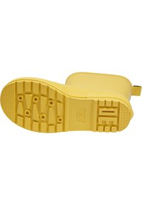 Žlutá pryžová podrážka boty má texturovaný grip s různými tvary, včetně trojúhelníků a kruhů, pro trakci a stabilitu.