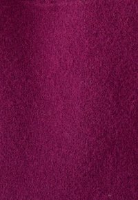 Tela de fieltro morado con una textura suave; presenta un aspecto uniforme y difuso con sutiles variaciones de tonalidad en toda la superficie.