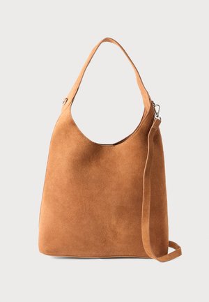 Bolso de hombro de ante marrón con una sola correa y una correa larga desmontable adicional sobre un fondo blanco liso.