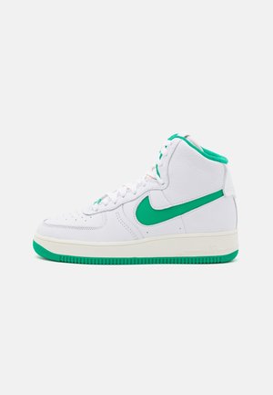 Baskets montantes blanches avec semelle verte, virgule Nike verte et doublure intérieure verte, montrées de profil sur un fond uni.