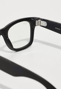 Black rectangular sunglasses with clear lenses. Matte finish with metal hinges. Features engraved logo on the inner arm.