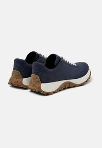 Sneaker blu navy con un mix di materiale scamosciato e liscio, dotati di una suola bianca e una suola esterna in gomma marrone testurizzata, design con lacci.