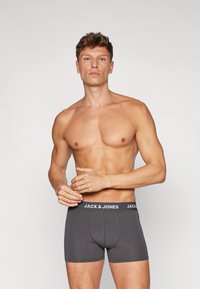 Graue Boxer-Briefs mit einer enganliegenden Passform und einem kontrastierenden elastischen Bund, der das Logo "JACK & JONES" trägt. Glatte Stoffstruktur.