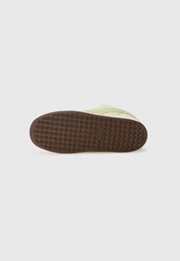Light green sneaker with a textured brown rubber sole featuring a diamond pattern and reinforced toe area, smooth upper and flexible design.