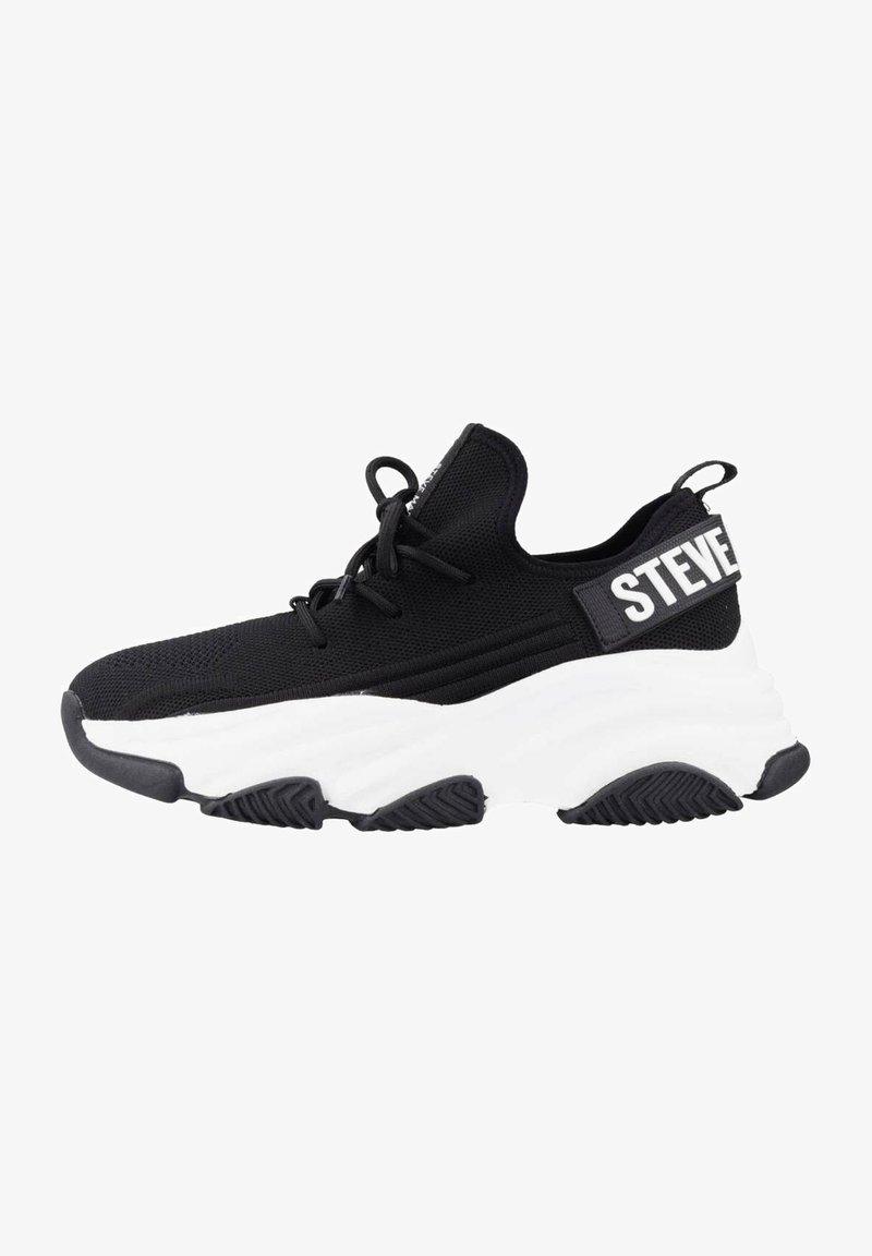 Chaussure de sport noire avec un upper en tricot texturé, semelle blanche rembourrée et une sangle avec "STEVE" en lettres majuscules à l'arrière.