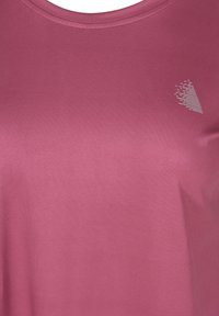 Koszulka z krótkim rękawem i okrągłym dekoltem w jednolitym ciemnoróżowym kolorze. Na górnej lewej stronie znajduje się subtelny srebrny wzór. Gładka faktura.