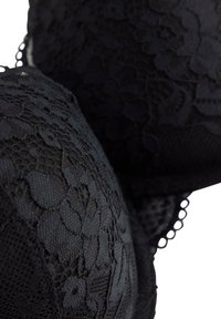 Sort blondestof med blomsterprint og bølgede kanter, der viser tekstur og indviklede detaljer tæt på.