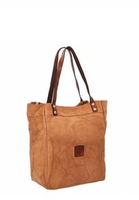 Bruine canvas tas met gladde leren schouderbanden, met een gestikt label aan de voorkant en een licht gerimpelde textuur.