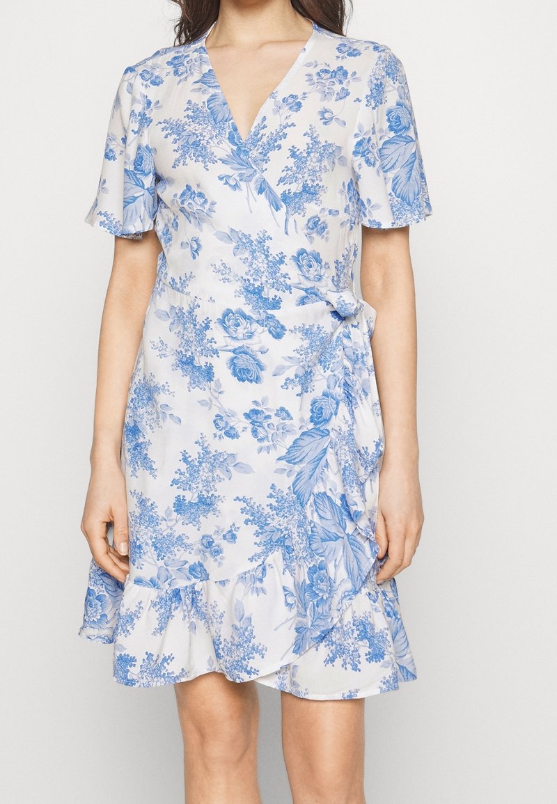 Robe portefeuille légère à fleurs avec un motif bleu sur fond blanc, manches courtes, encolure en V et ourlet volanté.
