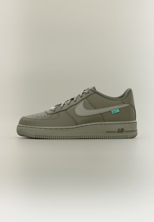 Baskets Nike Air vertes à profil bas avec un swoosh blanc, design à lacets, bout perforé et petite étiquette turquoise près du talon sur fond uni.