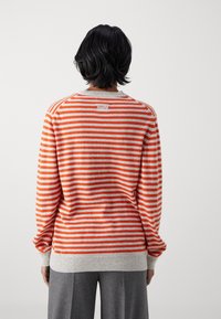 Maglione a righe arancione e grigio, con collo rotondo, polsini e orlo a coste, dalla texture morbida e dalla vestibilità rilassata.