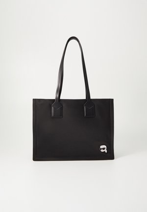 Zwarte rechthoekige tote bag met dubbele dunne handvatten en een klein cartoongezicht met zonnebril op de rechterbenedenhoek.