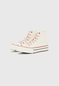 Καμβά παπούτσια τύπου ψηλού με εκτύπωση κόκκινης καρδιάς σε κρεμ αποχρώσεις, με κόκκινα κορδόνια, λευκή άκρη στα δάχτυλα και πολύχρωμες ρίγες στη σόλα.