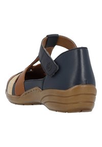 Sandaal de color marino, marrón y crema con diseño cortado, tira de velcro y suela texturizada. Fabricado con cuero y materiales sintéticos para mayor comodidad.