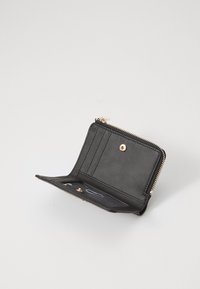 Porte-monnaie en cuir noir avec fermeture zippée, comportant des emplacements pour cartes, un bouton-pression et une texture lisse. Des accents en métal doré sont visibles.