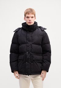 Black puffer jacket with a high collar, snap buttons, and four pockets. Features a smooth texture and a slightly shiny finish.