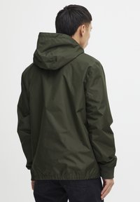 Dark green, lightweight jacket with a hood, elastic cuffs, and hem. Smooth texture, casual fit, and minimalistic design. No visible logos.