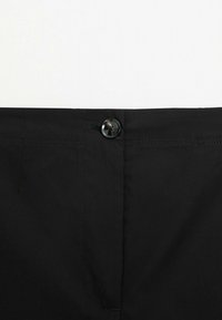 Ceinture de pantalon noir avec un seul bouton noir fixé au centre sur fond blanc.