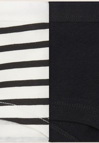 Czarno-białe paskowane majtki po lewej, jednolite czarne po prawej. Obie pary wykonane z miękkiego materiału, z elastycznymi pasami i szwami.