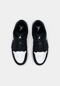 Black and white sneakers with perforated toe box, black laces, and Air Jordan logo on the tongue and side. Durable material with smooth texture.