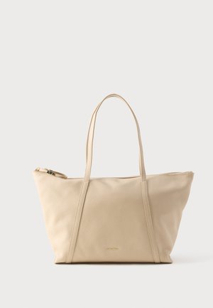 Beige leather tote bag with two long handles, textured surface, zipper closure, and small gold brand logo centered on front.