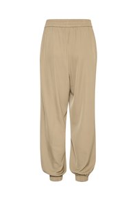 Beige kalhoty s elastickým pasem, volného střihu, se zužujícími se manžetami a hladkým materiálem. Jednoduchý design bez vzorů nebo kovových detailů.