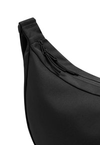 Czarna torba na ramię z gładką, teksturowaną powierzchnią. Posiada zakrzywiony kształt oraz zamek błyskawiczny z czarnymi uchwytami.