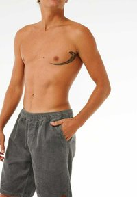 Grijze corduroy shorts met een elastische tailleband en zijzakken. De linkerkant van de borst heeft een zwarte tatoeage in een golfontwerp.